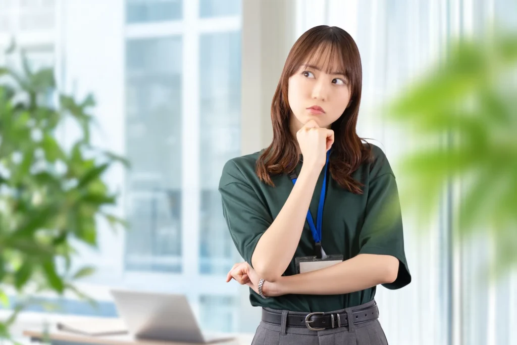 腕を組み首をかしげながら考える女性