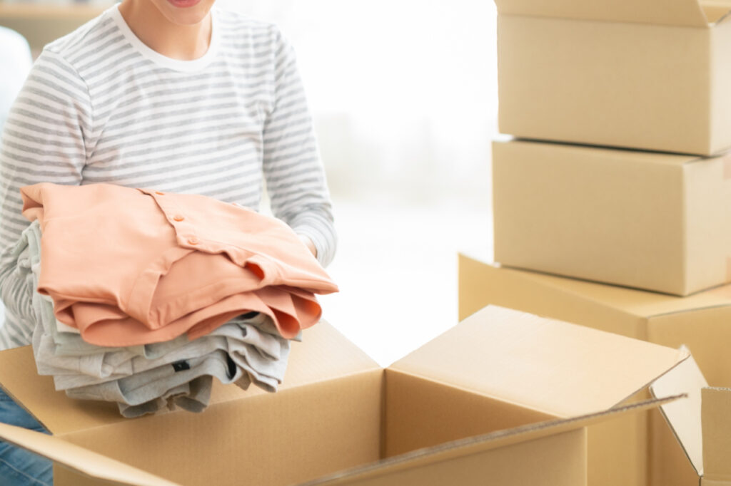 段ボールに囲まれながら引っ越しの荷造りをしている女性