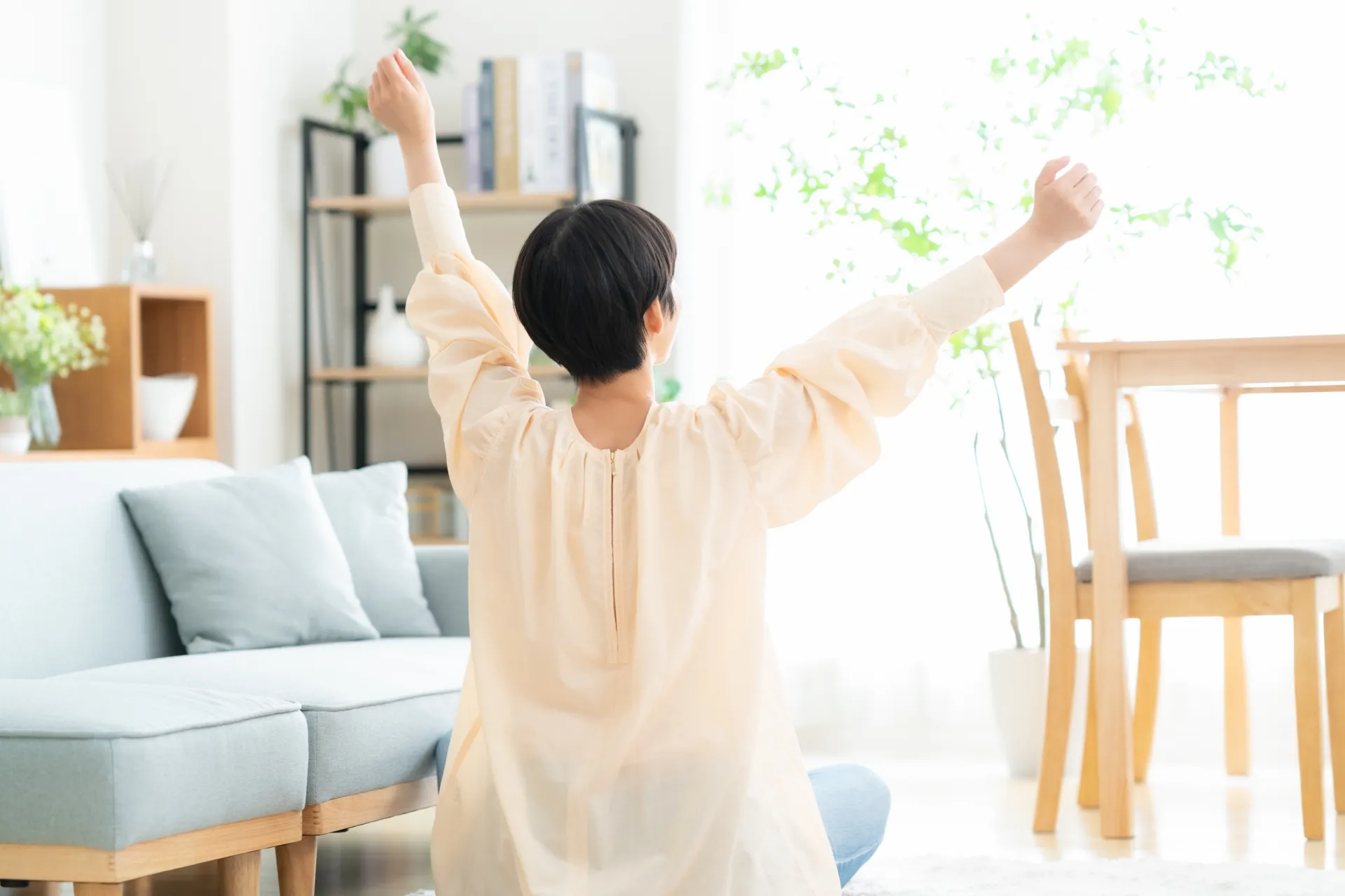 引っ越しして朝日に向かい伸びをしている女性