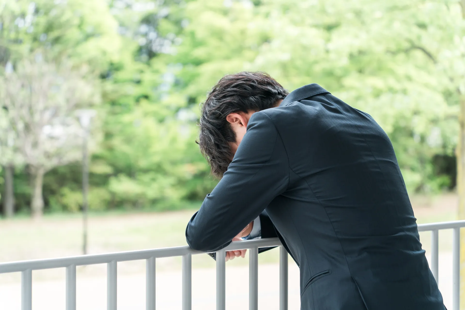 うなだれるスーツの男性（後ろ姿）