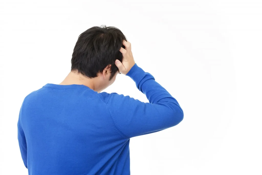 頭を抱える中年男性の後ろ姿