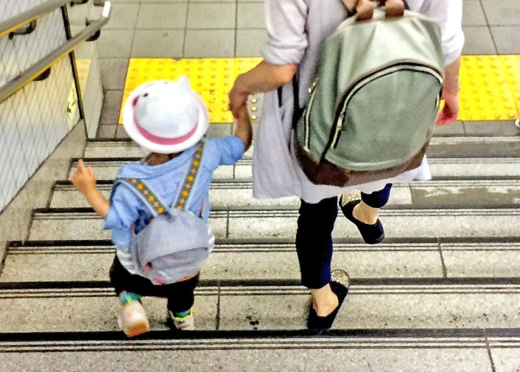 ママが幼稚園児の子供と手を繋いでJRの階段を下りている後ろ姿