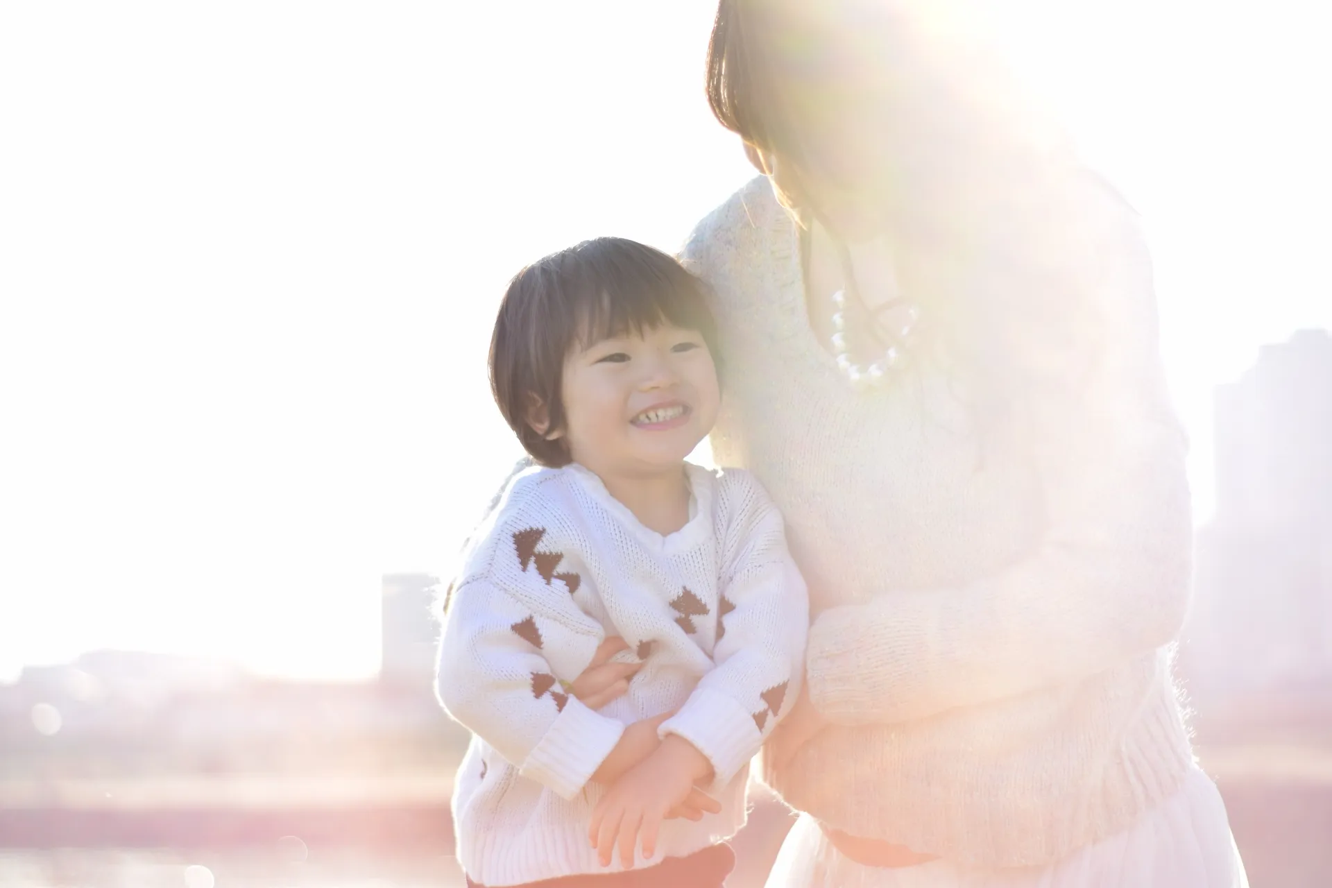 夕日をバックに寄り添うママと幼稚園児の子供