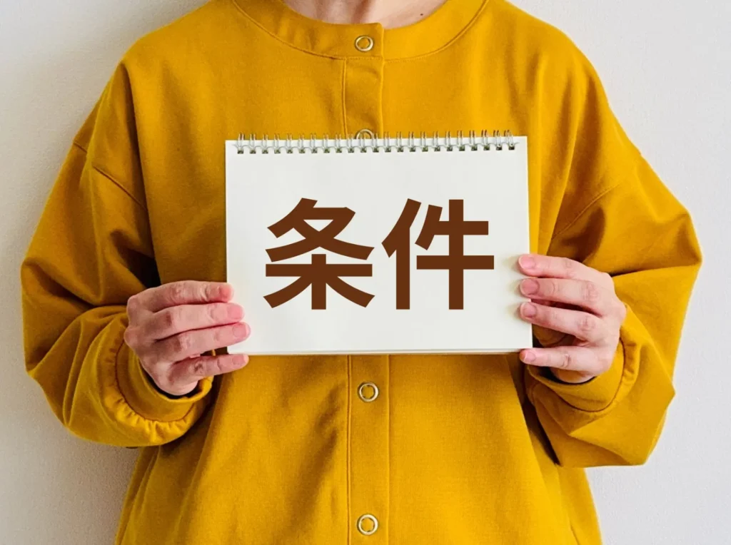 「条件」と書いた紙を持つ女性