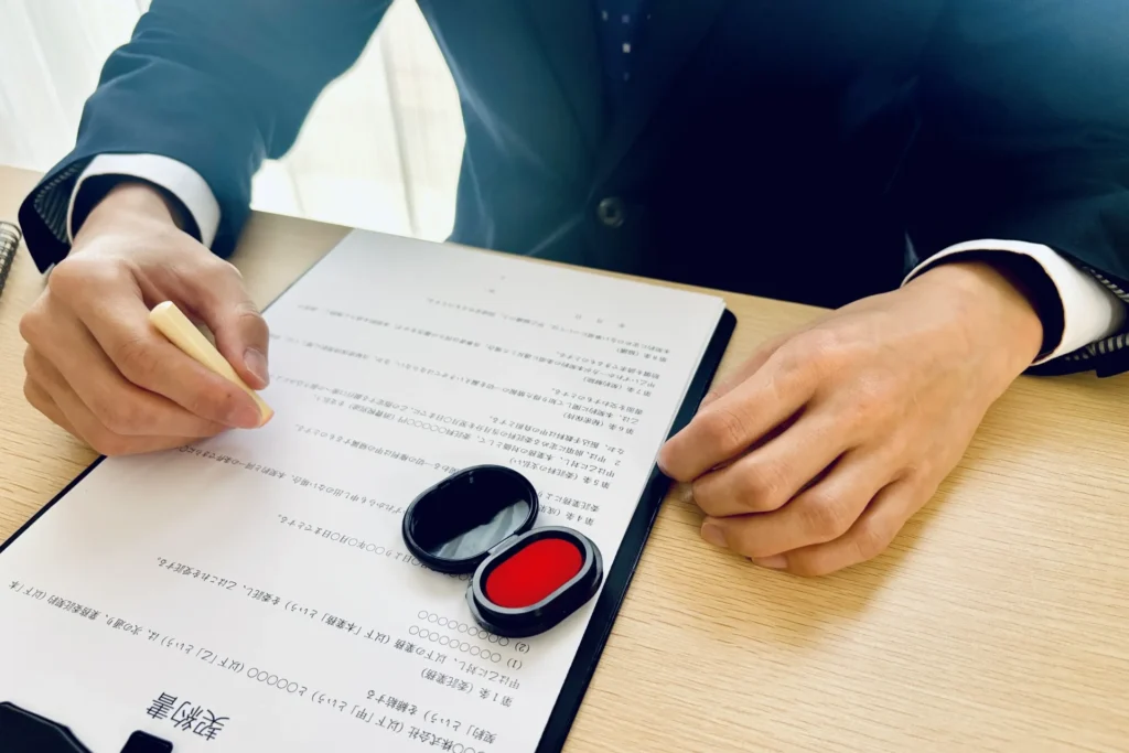 契約書と印鑑（スーツの男性の手元）