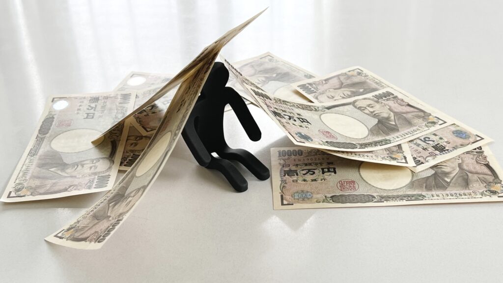 一万円札の数枚に囲まれる黒い小さな小人